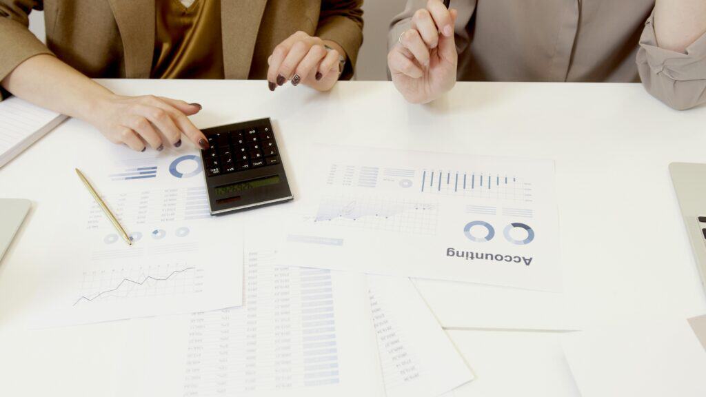 woman using calculator and some accounting papers scattered on the table