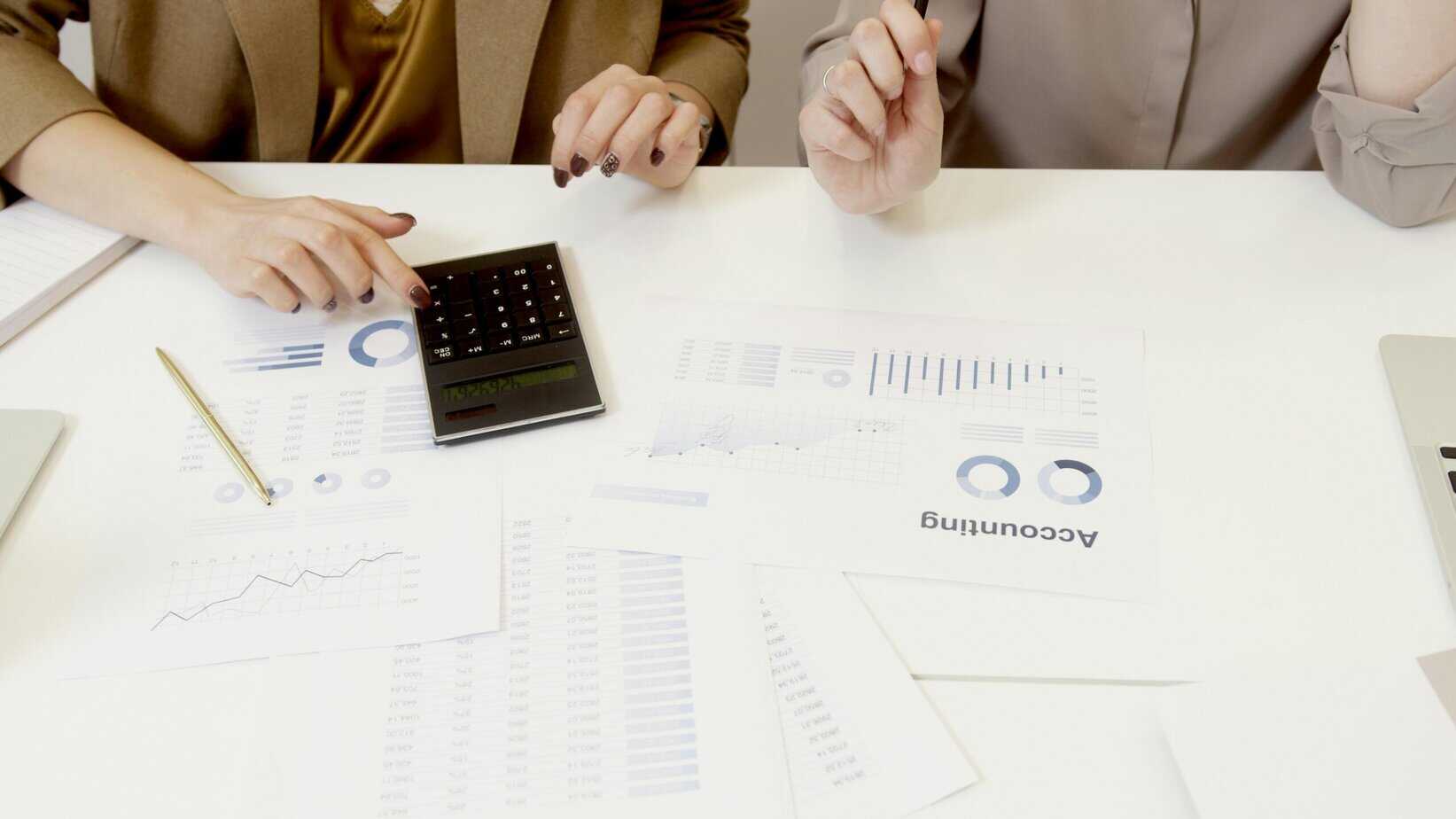woman using calculator and some accounting papers scattered on the table