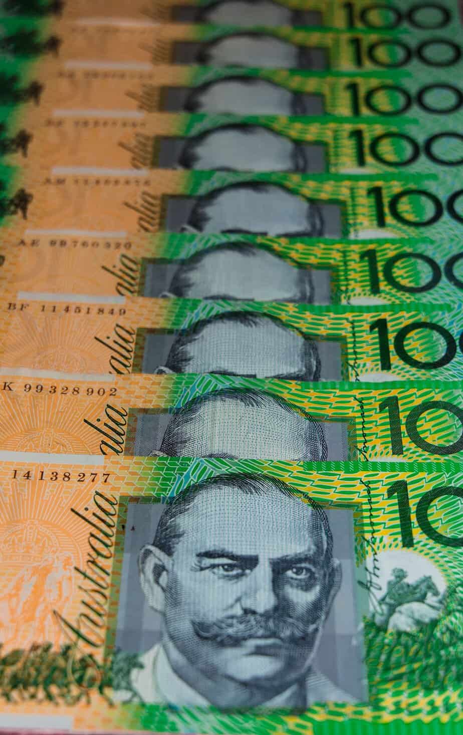 Vertical close-up of stacked Australian 100-dollar banknotes showcasing currency details.